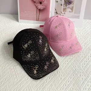 Détail de casquettes en coton noir et rose avec motifs Love en strass arc-en-ciel
