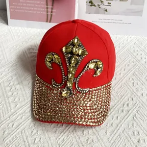 Detailed view of red denim baseball cap with gold fleur-de-lis rhinestone pattern