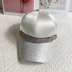 Detailed view of white satin baseball cap with silver glitter brim and rhinestone buckle