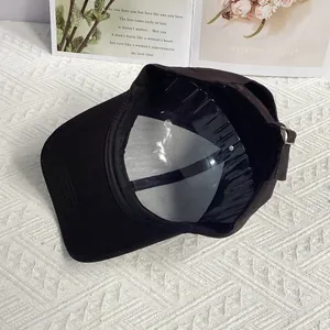 Detail view of black baseball cap interior with adjustable silver metal buckle and sweatband