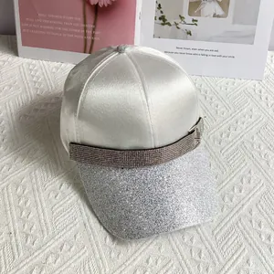 Detail of white satin baseball cap with rhinestone buckle and silver glitter brim detail