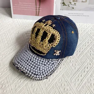 Detail of crown embroidery and pearl embellishments on a denim baseball cap