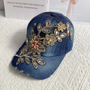 Detail der blauen Denim-Basecap mit goldener Blumenstickerei und eingelegten Strasssteinen