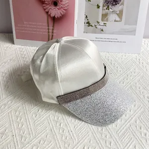 Detail of white satin baseball cap with rhinestone buckle and silver glitter brim