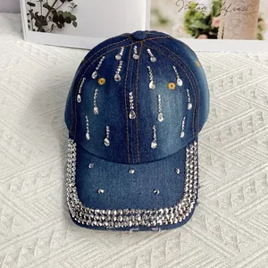 Dettaglio di motivi in strass e ricamo a fiori gialli su cappellino da baseball denim