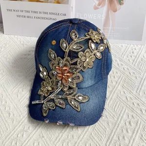 Detailansicht der Denim-Baseballkappe mit goldenen Blumenstickereien und Strasssteinen