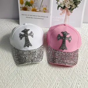 Flat lay of white and pink baseball caps featuring rhinestone cross patches and sparkling brims