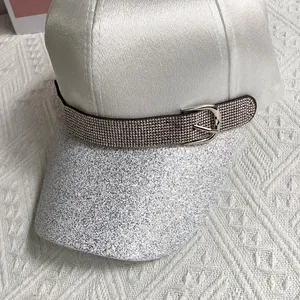 Close-up of sparkling sequin brim and rhinestone buckle on white satin baseball cap