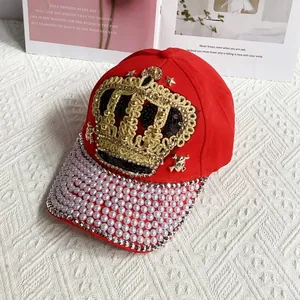 Close-up of red baseball cap with golden crown patch, pearls, and rhinestone detail
