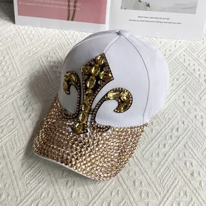 Detail of white cotton baseball cap with amber fleur-de-lis gemstone and rhinestone brim
