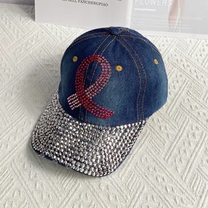 Detailed view of dark blue denim baseball cap featuring pink rhinestone ribbon and studded brim