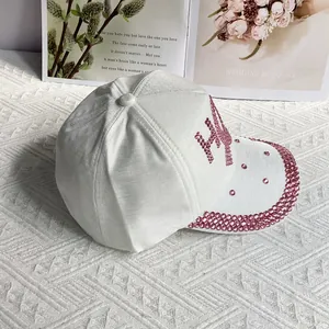 Detailed view of pink rhinestones and textured fabric on a white baseball cap