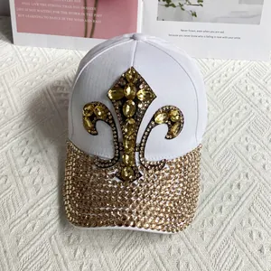 Detail of fleur-de-lis gold rhinestone emblem on white canvas denim baseball cap