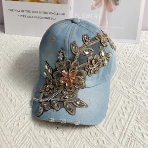 Detail einer hellblauen Jeans-Baseballkappe mit goldener Blumenstickerei und Strass