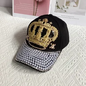 Macro shot of black denim cap with golden crown embroidery and white pearl brim details