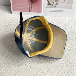Detail view of denim baseball cap interior with yellow edging and leather adjustment strap