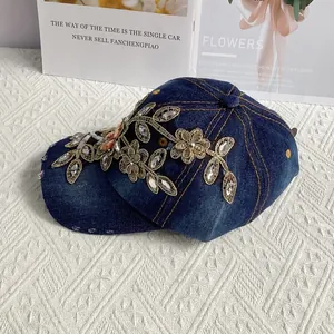 Detail der goldenen Blumenstickerei und Strasssteine auf Denim-Baseballkappe