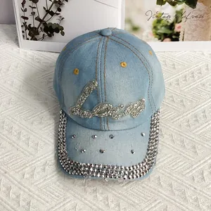 Dettaglio del motivo Love in strass e borchie di cristallo su berretto denim azzurro