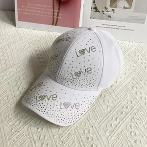 Détail de la casquette blanche en coton avec lettrage love et motifs cœur en strass colorés