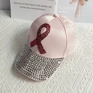 Close-up of pink satin baseball cap featuring red rhinestone ribbon and jeweled brim
