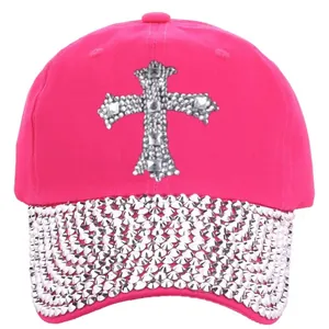 Close-up of pink baseball cap with rhinestone cross patch and shimmering diamond brim
