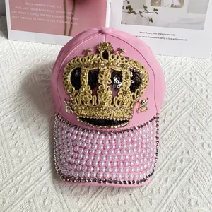 Close-up of pink baseball cap featuring golden crown embroidery and pearl beaded brim