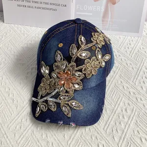 Nahaufnahme der handgestickten Blumen und Strasssteine auf der blauen Denim-Baseballkappe