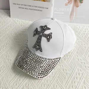 Close-up of white baseball cap with rhinestone cross and studded brim detail
