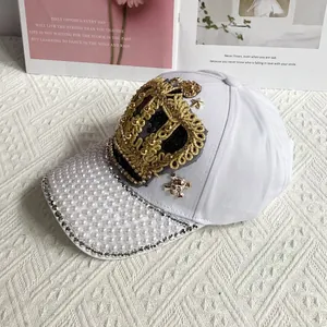 Close-up of white crown baseball cap with faux pearls, rhinestones and metal charms