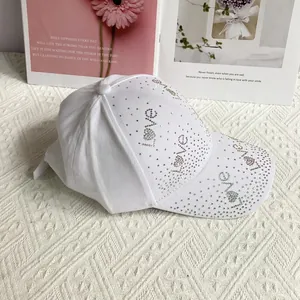 Détail d'une casquette en coton blanc avec inscription LOVE en strass colorés brillants