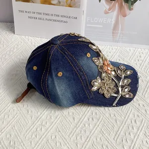 Detail von bestickten Blumen und bunten Strasssteinen auf einer blauen Denim-Kappe