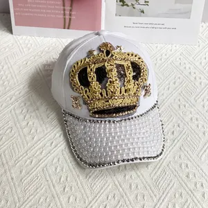 Detail of white baseball cap with golden crown embroidery and white pearl brim accents