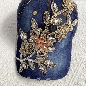 Nahaufnahme goldener Blumenstickerei und Steinchen auf dunkelblauer Denim-Baseballkappe