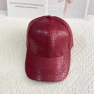 Close-up of wine red baseball cap with crocodile leather texture on white waffle fabric