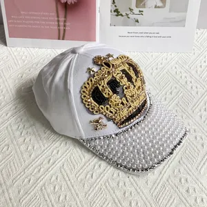 Detail of white baseball cap featuring crown embroidery, pearls and rhinestones