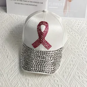 Close-up of white satin baseball cap with pink rhinestone ribbon and silver crystals