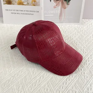 Detail view of burgundy baseball cap with faux crocodile texture on a stylish display