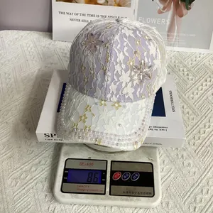Vue détaillée d'une casquette en dentelle avec perles et strass sur une balance pesant 86g