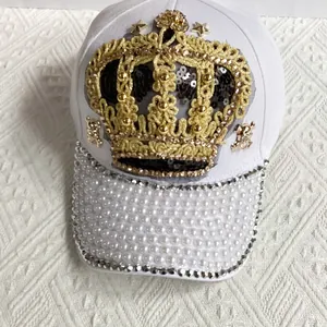 Detail of white baseball cap with gold crown embroidery, pearls and rhinestones on brim