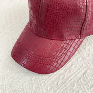 Close-up of deep red crocodile embossed faux leather texture on baseball cap brim