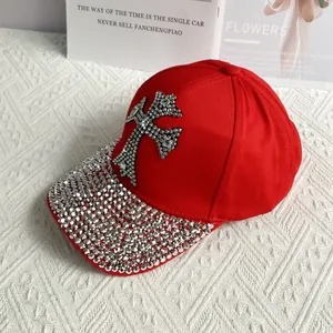 Detail of red denim baseball cap featuring rhinestone cross and studded brim accents