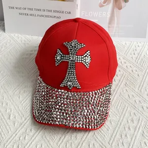Close-up of a red baseball cap featuring a large rhinestone cross and crystal brim