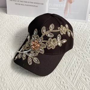 Detail der Goldfaden-Blumenstickerei und Strasssteine auf schwarzer Baseballkappe