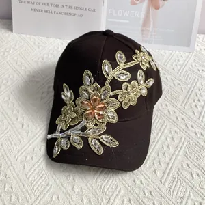 Detail der Baseballkappe mit goldener Blumenstickerei und funkelnden Kristallverzierungen