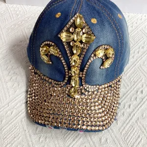 Detail of blue denim cap featuring fleur-de-lis crystal patterns and rhinestone brim
