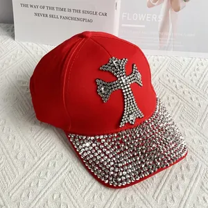 Close-up of red denim baseball cap with rhinestone cross and studded brim detail