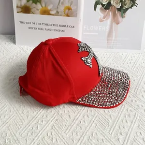 Close-up of sparkling silver rhinestones on a red cotton baseball cap with cross detail