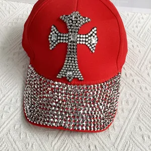 Close-up of sparkling silver rhinestones on a red cotton baseball cap with a cross design