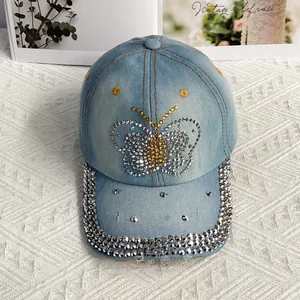 Gros plan du motif papillon en strass étincelants sur une casquette en denim bleu clair