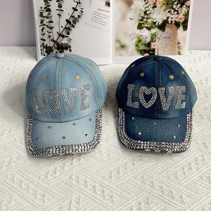 Détail de casquettes en jean avec motifs LOVE en strass, coloris bleu clair et foncé